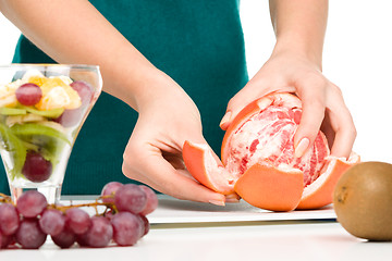 Image showing Cook is peeling grapefruit for fruit dessert