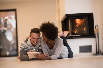 Image showing multiethnic couple used tablet computer on the floor