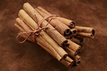 Image showing a bunch of cinnamon sticks on brown background