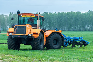 Image showing Tractor operator plows the site in rain