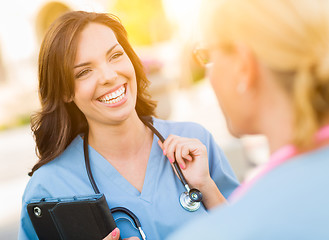 Image showing Two Young Adult Professional Female Doctors or Nurses Talking Ou