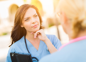 Image showing Two Young Adult Professional Female Doctors or Nurses Talking Ou