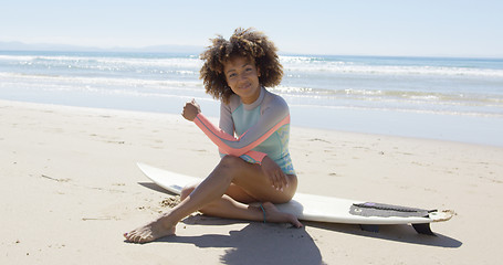 Image showing Happy female sitting on a surfboard