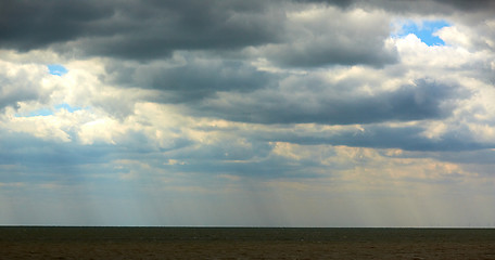 Image showing Sun beam through heavy sky over calm sea