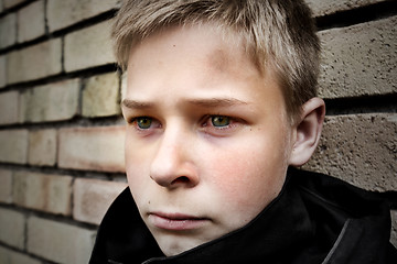 Image showing upset boy leaning against a wall