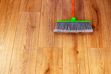 Image showing cleaning wooden floor with green plastic broom