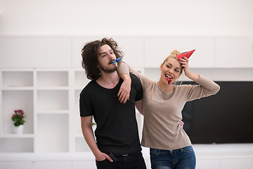 Image showing couple in party hats blowing in whistle