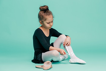 Image showing Beautiful little ballerina in black dress for dancing puting on foot pointe shoes