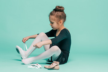 Image showing Beautiful little ballerina in black dress for dancing puting on foot pointe shoes