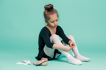 Image showing Beautiful little ballerina in black dress for dancing puting on foot pointe shoes