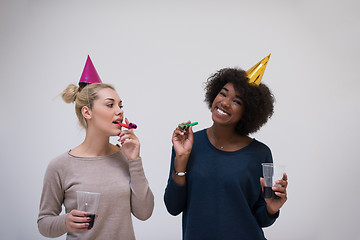 Image showing smiling women in party caps blowing to whistles