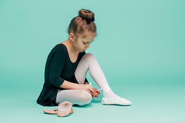 Image showing Beautiful little ballerina in black dress for dancing puting on foot pointe shoes