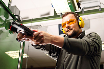 Image showing Shooting range. Shooting a gun at a shooting range. The man at the shooting reloads pistol