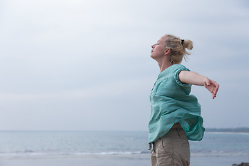 Image showing Free woman enjoying windy weather on beach on overcast day