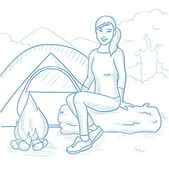 Image showing Woman sitting on log near campfire in the camping.