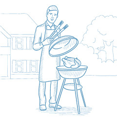 Image showing Man cooking chicken on barbecue grill.