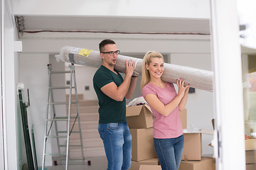 Image showing couple carrying a carpet moving in to new home