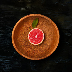 Image showing Grapefruit citrus fruit halves on wooden plate