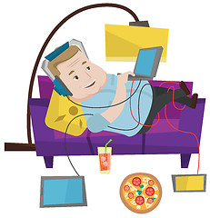 Image showing Man lying on sofa with many gadgets.