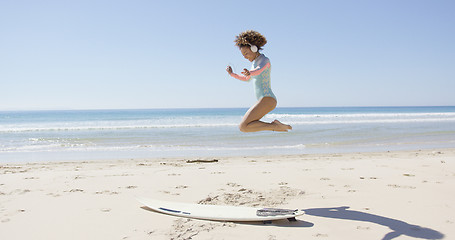 Image showing Female listening music and jumping on beach