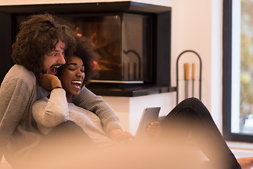 Image showing multiethnic couple used tablet computer on the floor