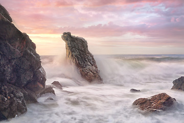 Image showing Wave surges through rocky coastline at sunrise