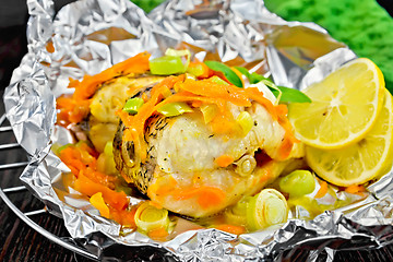 Image showing Pike with carrots and lemon in foil on dark board