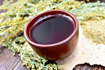 Image showing Tea with wormwood in clay cup on dark board