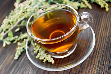 Image showing Tea with wormwood in glass cup on dark board