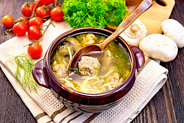 Image showing Soup with meatballs and spoon in clay bowl on napkin