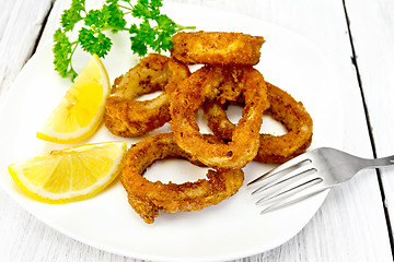 Image showing Calamari fried with lemon in plate on board