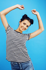 Image showing young pretty teenage modern hipster girl posing emotional happy smiling on blue background, lifestyle people concept 