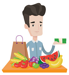 Image showing Young man standing at the table with shopping bag