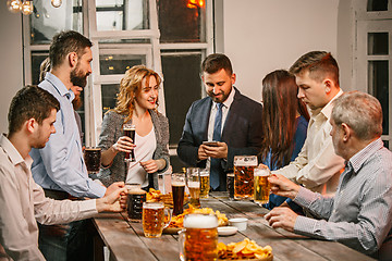 Image showing Group of friends enjoying evening drinks with beer