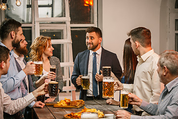 Image showing Group of friends enjoying evening drinks with beer