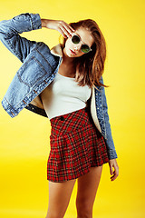 Image showing young pretty teenage hipster girl posing emotional happy smiling on yellow background, lifestyle people concept