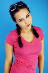 Image showing young pretty teenage modern hipster girl posing emotional happy smiling on blue background, lifestyle people concept 