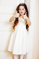 Image showing little cute girl at home, opening door well-dressed in white dre