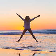 Image showing Young beautiful woman jumping in the beach.