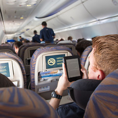 Image showing Male passenger reading e-book on electronic reader on airplane.