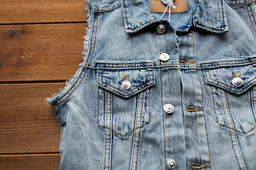 Image showing close up of denim vest or waistcoat on wood