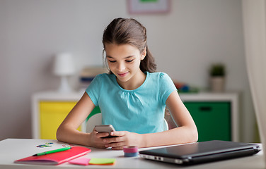 Image showing girl with smartphone distracting from homework