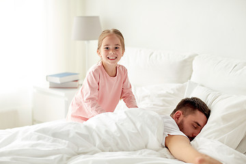 Image showing little girl waking her sleeping father up in bed