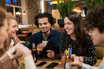 Image showing friends with drinks, money and bill at bar