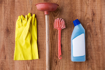 Image showing plunger with cleaning stuff on wooden background