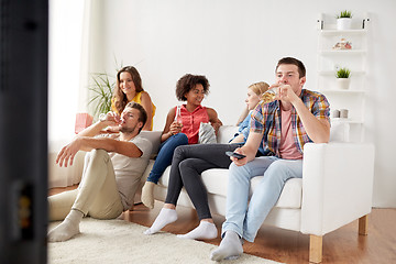 Image showing friends with popcorn and beer watching tv at home