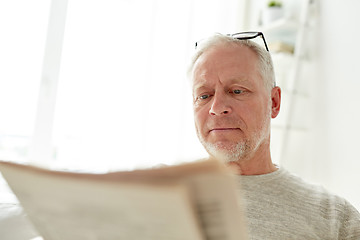 Image showing close up of senior man reading newspaper at home