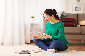 Image showing happy woman with money and travel map at home