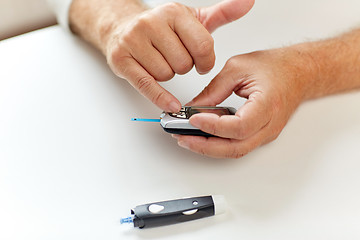 Image showing senior man with glucometer checking blood sugar