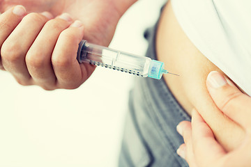 Image showing close up of hands making injection by insulin pen